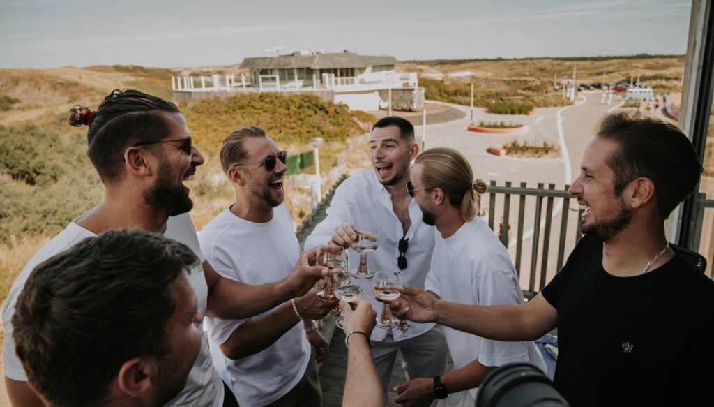 Bräutigam stößt beim Getting Ready mit Freunden an, alle lachen