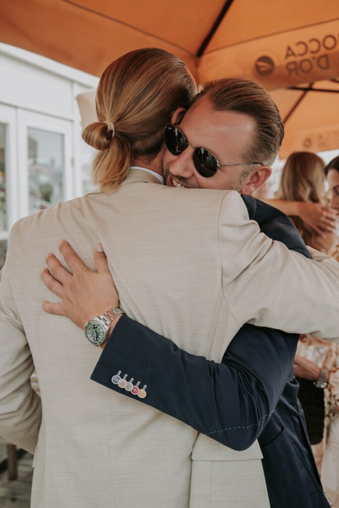 Trauzeuge umarmt den Bräutigam nach der Trauung, Glückwünsche und Freude