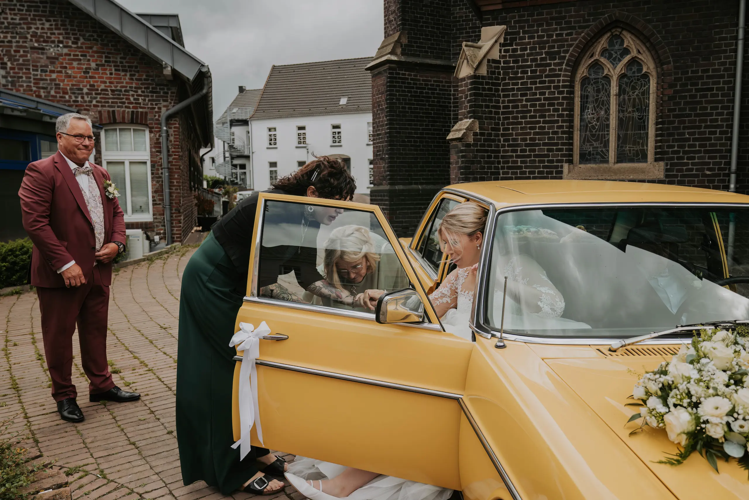 Marina steigt vor der St.-Clemens-Kirche aus dem gelben Oldtimer