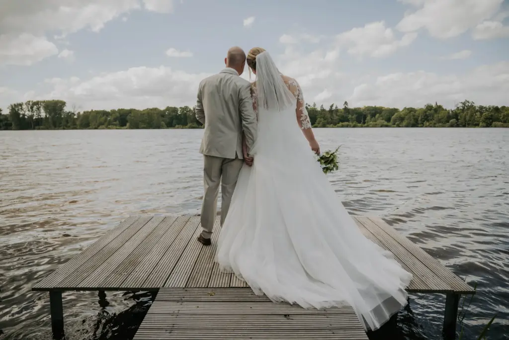 Marina und Dennis stehen von hinten auf dem Steg und schauen auf den See