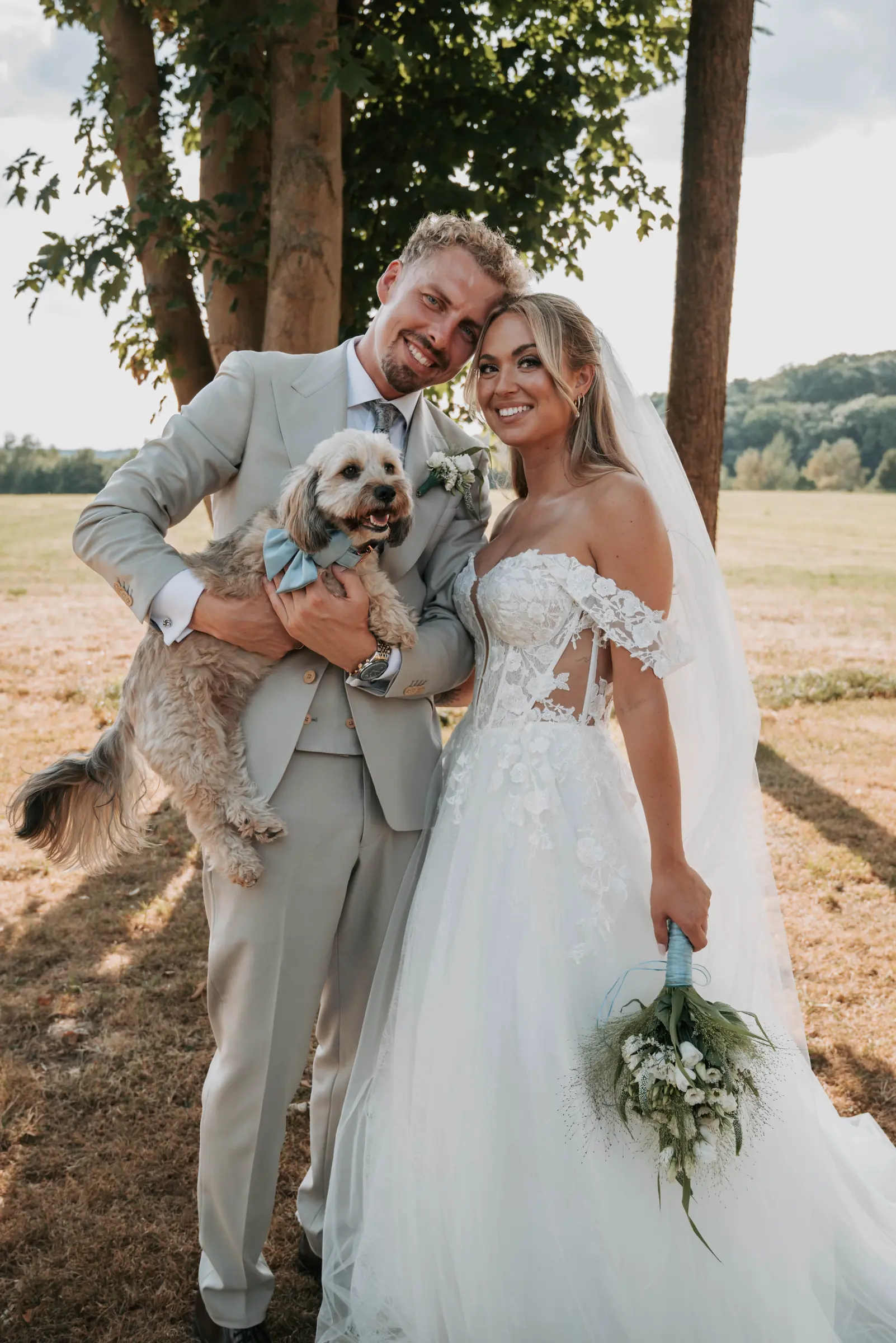 Chanti und Alex lächeln beim Paarshooting gemeinsam mit ihrem Hund.